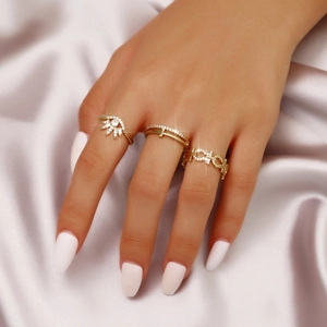 Three-piece gold ring set featuring sun eye, cross, and chain designs with crystals