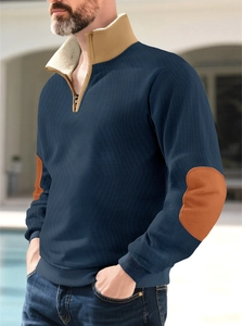Detail of navy quarter-zip sweatshirt with camel collar and orange elbow patch on model