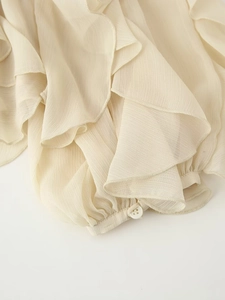 Détail du poignet d'une chemise en mousseline beige avec volants superposés élégants