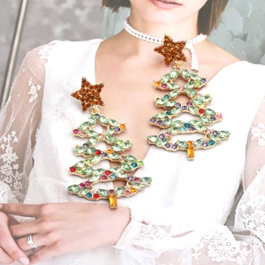 Detailed view of oversized Christmas tree earrings with colorful rhinestones on a model