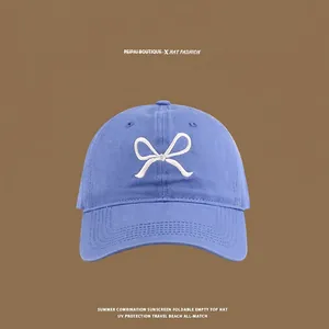 Close-up of blue cotton baseball cap showing detailed white butterfly embroidery on front