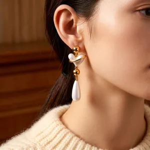 Vintage style gold heart pearl drop earrings shown on a model with white sweater
