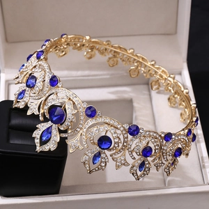 Close-up of golden bridal crown with blue gemstones and rhinestones in a white box