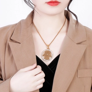 Gold Hamsa Hand pendant necklace with crystals worn by a model in a blazer