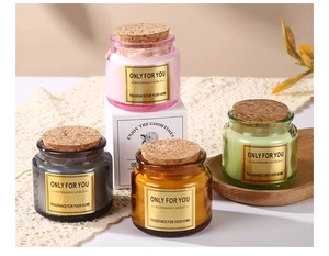 Detail view of four colored glass scented candles with cork lids on a lace tablecloth