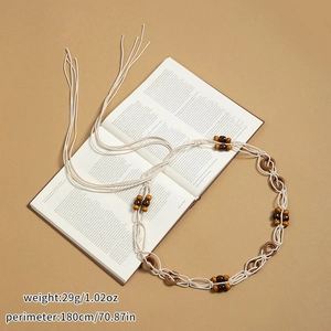 Détail d'une ceinture tressée main avec perles en bois brun sur un livre ouvert