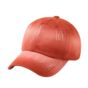 Detail view of brick red washed cotton baseball cap featuring stylish distressed frayed holes