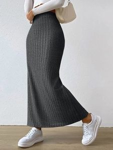 Detail of dark grey ribbed knit maxi skirt featuring high waist and side slit on model