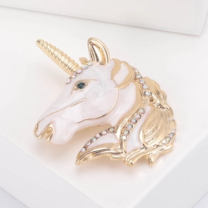 Close-up of pink enamel unicorn brooch with sparkling crystals on gold metal plating