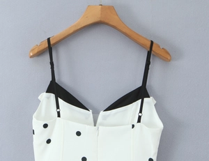 Gros plan sur le décolleté en V et les fines bretelles de cette robe à pois