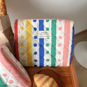 Dettaglio della borsa da trucco trapuntata con strisce arcobaleno e pois colorati