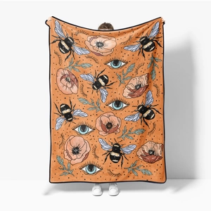 Detail of large flannel blanket with bee and poppy print held to show size and texture
