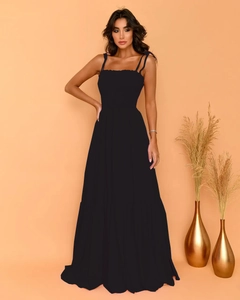 Detail of black maxi dress featuring thin straps and elastic ruched bodice with flared skirt