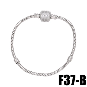 Macro detail of silver snake chain bracelet featuring a sparkling rhinestone cylinder charm