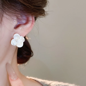 Detail of elegant white zircon flower stud earring worn on ear with soft matte finish