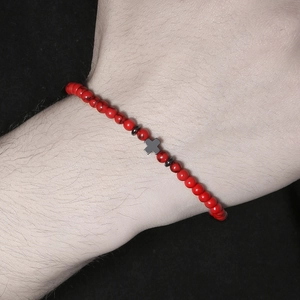 Macro detail of men's bracelet with red turquoise beads and metal cross on wrist