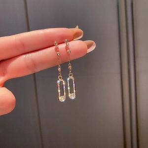 Détail de longues boucles d'oreilles dorées à pampilles avec strass tenues à la main