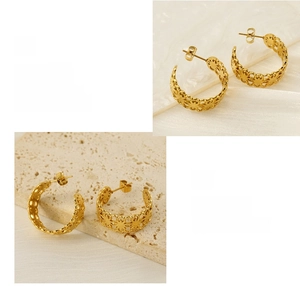 Detailed view of C-shaped gold earrings featuring hollow floral patterns and 18K plating