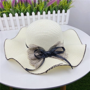 Close-up of beige sun hat featuring wavy brim and delicate double-layered bow detail