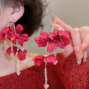 Close-up of red fabric flower earrings with crystal fringe and heart beads on a model