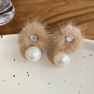 Detail of plush khaki faux fur earrings with pearl drop and rhinestones on ceramic tray