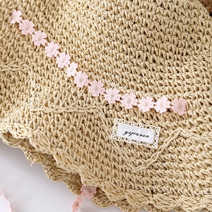 Women's straw sun hat with delicate pink floral lace trim for seaside vacation wear
