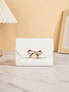 Macro detail of white PU leather wallet featuring a polished gold bow metal clasp