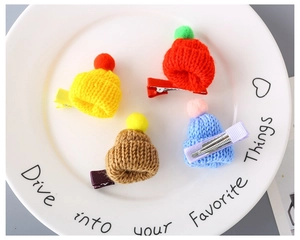 Detailed view of four colorful mini knitted hat hair clips on a white ceramic plate