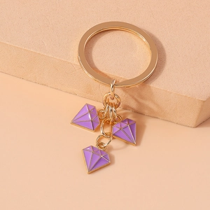 Detail view of golden keychain featuring three purple diamond-shaped enamel pendants