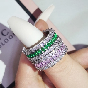 Macro detail of luxury stacked rings with marquise-cut emerald and violet zirconias