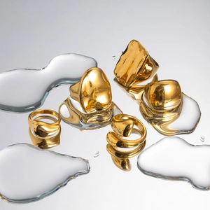 Artistic layout of golden liquid-metal drop rings on a reflective surface with water drops