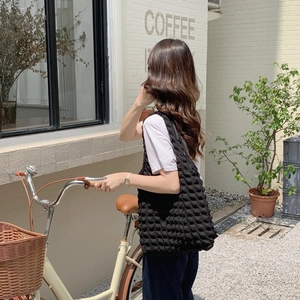 Outdoor shot of a black bubble texture shoulder bag worn by a model near a cafe