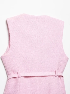 Détail macro du tissu en tweed rose et de la ceinture arrière de ce gilet femme