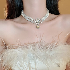Close-up of double-layer pearl necklace with diamond pendant and teardrop gem