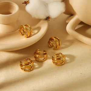 Set of five golden multi-layered titanium steel ear cuffs displayed on a ceramic base