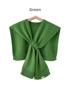 Detail view of the green knitted shawl showing the ribbed hem and elegant front knot design