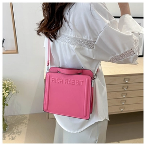 Detail of pink leather tote bag with RICH RABBIT embossed logo worn by a model