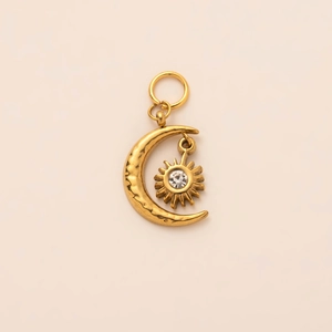 Detail of 18K gold-plated sun and moon pendant with a clear gemstone on textured metal