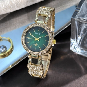 Détails d'une montre dorée pour femme sertie de strass avec un cadran vert émeraude