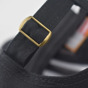Gros plan détaillé de la boucle réglable en métal bronze sur la casquette en coton noir