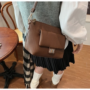 Détail d'un sac à bandoulière marron plissé avec fermoir rotatif doré et texture en cuir PU