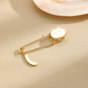 Detail of cute cat enamel brooch with a swinging moon tail on a gold safety pin