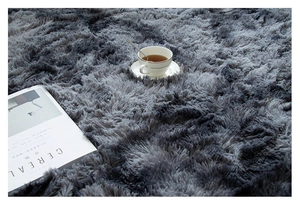 Close-up of grey tie-dye plush round rug featuring long shaggy fibers and soft texture