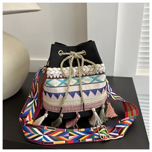 Detail of ethnic embroidered bucket bag with colorful tassels and gold drawstring closure
