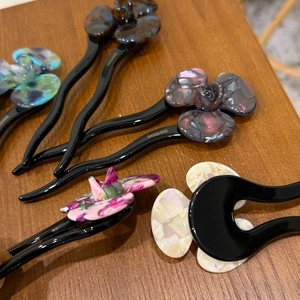 Detailed view of assorted acetic acid flower hair pins with unique textures on wood