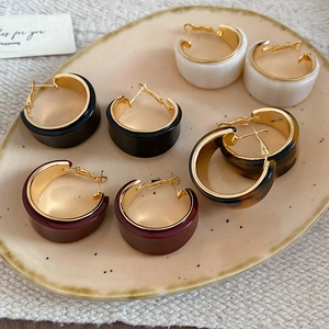 Détail de quatre paires de boucles d'oreilles créoles en résine aux couleurs rétro sur plateau