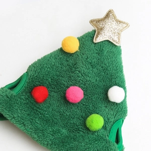 Detail showing plush green Christmas tree pet hat with golden star and colorful pom-poms