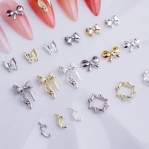 Detailed macro view of gold and silver metallic bowknot 3D nail art charms on white background