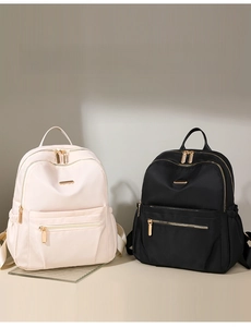 Detail view of nylon backpacks in black and beige with multi-zippered compartments