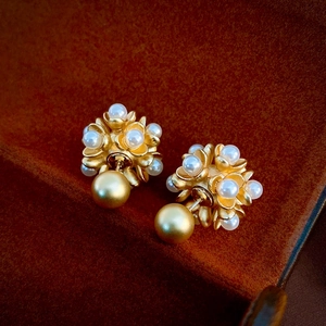 Vintage gold flower stud earrings with pearls on brown velvet background